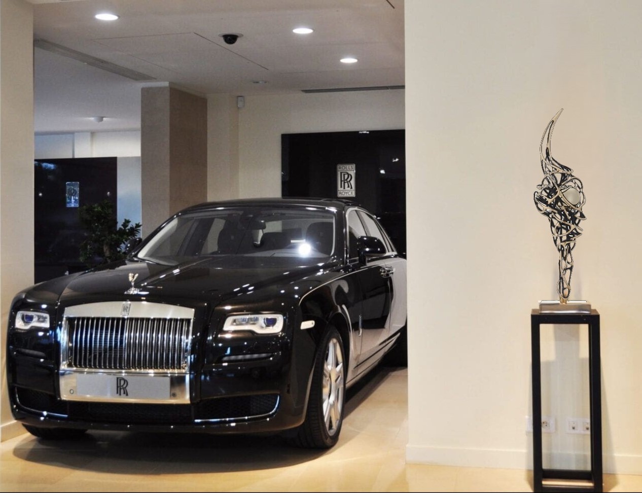 Detailed view of the intricate feathers and flowing lines of Gianfranco Meggiato's bronze sculpture next to a Rolls Royce, showcasing the craftsmanship and fluidity of the design.